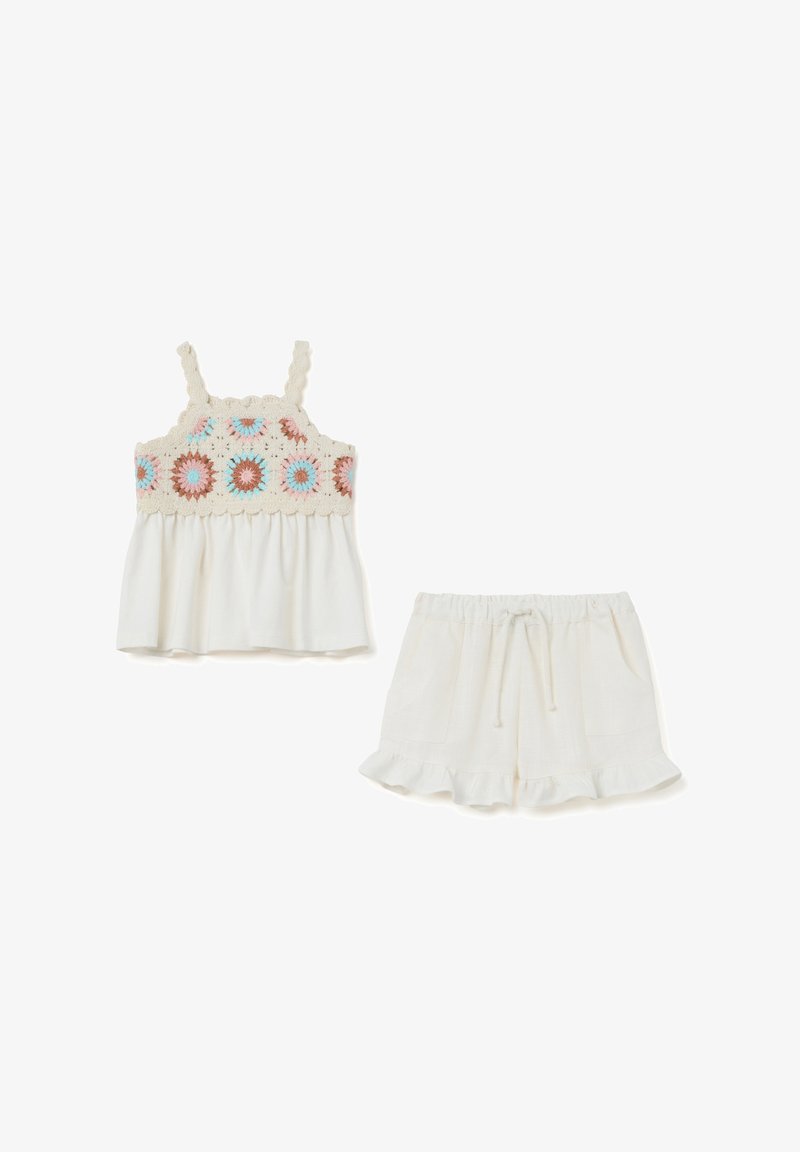 Zweiteiliges Outfit, bestehend aus einem weißen Tanktop mit einem bunten, gestickten Blumenmuster und passenden weißen Shorts mit einem Rüschensaum.
