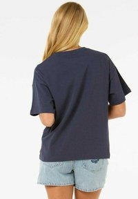 Camiseta de algodón azul marino con mangas cortas y un corte relajado. Presenta un cuello redondo, tejido texturizado y un diseño simple.