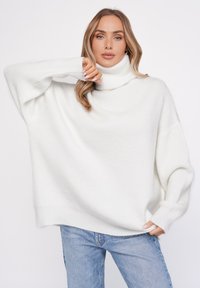 Biały, oversize'owy sweter z golfem, wykonany z teksturowanej dzianiny. Posiada luźne rękawy, wysoki kołnierz oraz luźny krój. Idealny do codziennych stylizacji z dżinsami.