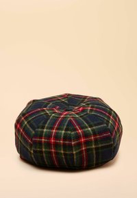 Okrągła poduszka w kratę w kolorach granatowym, zielonym i czerwonym, wykonana z wełny. Posiada pikowaną górę i przeszywane szwy. Teksturowany materiał z klasycznym wzorem w kratę.