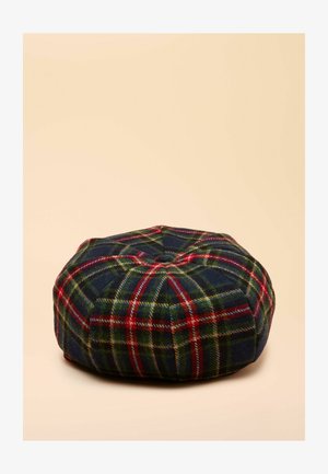 Okrągła poduszka w kratę w kolorach granatowym, zielonym i czerwonym, wykonana z wełny. Posiada pikowaną górę i przeszywane szwy. Teksturowany materiał z klasycznym wzorem w kratę.