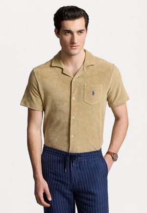 Korte mouwen, tan handdoekenstof shirt met een notch kraag, borstzak en blauwe logo-accent, gecombineerd met blauw gestreepte drawstring broek.