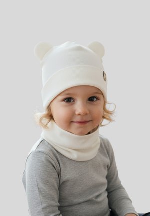 White knit beanie with bear ears and a matching neck warmer. Soft texture, simple design, and a small logo accent on the hat.
