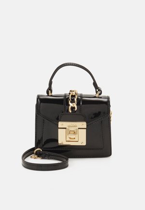 Kiiltävä musta käsilaukku yläkahvalla, kultaisella ketjuyksityiskohdalla, etupuolen kultaisella lukolla ja irrotettavalla olkahihnalla valkoisella taustalla.