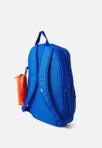 Sac à dos bleu avec un dos et des bretelles rembourrés, comprenant une poche latérale contenant une petite trousse d'accessoires orange. Tissu texturé et détails en maille.