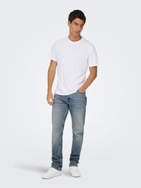 Camiseta de algodón blanca, jeans de mezclilla azul claro y zapatillas blancas. Ajuste casual, diseño de pierna recta, lisa sin patrones ni acentos.