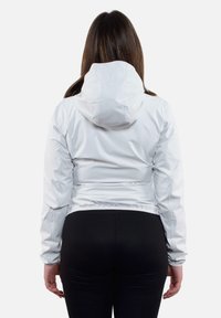 Giacca leggera bianca con cappuccio, caratterizzata da un design aderente e vita elastica. Texture liscia, hardware minimale e maniche lunghe.