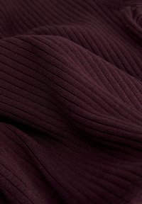 Tissu côtelé violet foncé avec des plis doux et des lignes verticales texturées, mettant en valeur l'élasticité et l'épaisseur du matériau.