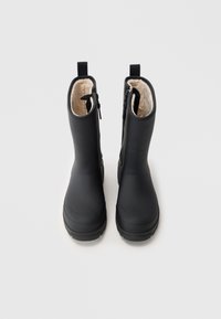 Bottes noires imperméables avec un extérieur lisse, doublure beige douce et fermeture éclair sur le côté. Bout arrondi et semelle texturée pour une meilleure adhérence.