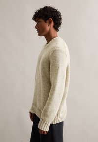 Pullover de malha em creme claro com um padrão pontilhado subtil, com bainha e punhos canelados, e um design em forma de V.