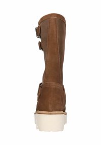 Bota de ante marrón hasta la rodilla con dos hebillas plateadas, suela blanca texturizada y punta redondeada, diseñada para un ajuste ceñido y uso al aire libre.