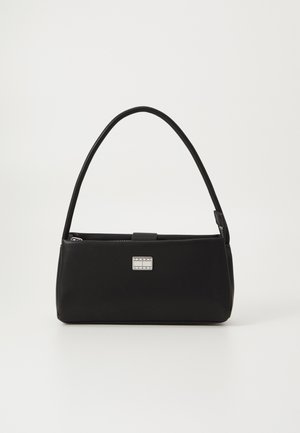 Bolso negro con una textura suave, forma rectangular y un asa curva. Presenta un detalle de logo metálico y cierre de cremallera.