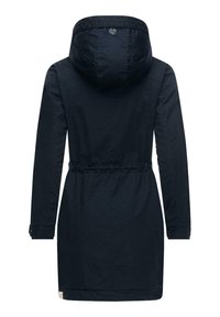 Veste bleu marine avec capuche, taille cintrée et manches longues. Texture lisse avec un détail de logo au dos et des poignets de manche boutonnés.