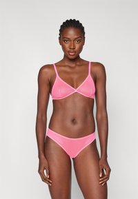 Bralette rosa e bikini abbinato realizzati in tessuto morbido con cuciture minime e spalline regolabili. Design semplice e materiale elasticizzato.