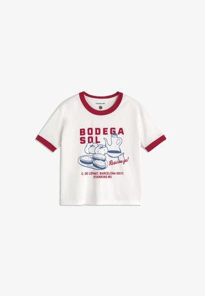 T-shirt blanc à manches courtes avec bordure rouge, texte rouge "Bodega Sol", illustration bleue de nourriture et bouteille, et texte rouge supplémentaire en bas.