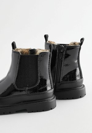 Stivaletti in vernice nera con cerniera laterale, pannello elastico, suola in gomma spessa e fodera in pelliccia sintetica leopardata.