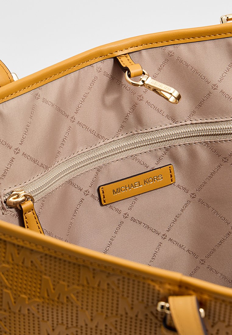 Gelbe Michael Kors Handtasche mit beigem Innenfutter, ausgestattet mit einem Reißverschlussfach und einem Markenetikett. Texturiertes Design mit auffälligen Hardware-Akzenten.