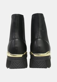 Stivaletti alla caviglia in pelle nera con pannelli elastici ai lati, dettaglio dorato sul tallone, suola in gomma con motivo a zigzag per una migliore trazione.