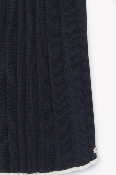 Tessuto a coste blu navy con plissettature verticali, dotato di un orlo color crema e un piccolo logo accentato nell'angolo in basso a destra.