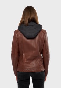 Giacca in pelle marrone con cappuccio grigio scuro. Presenta una texture liscia e un design aderente, con dettagli delle cuciture sulle spalle e sulle maniche.