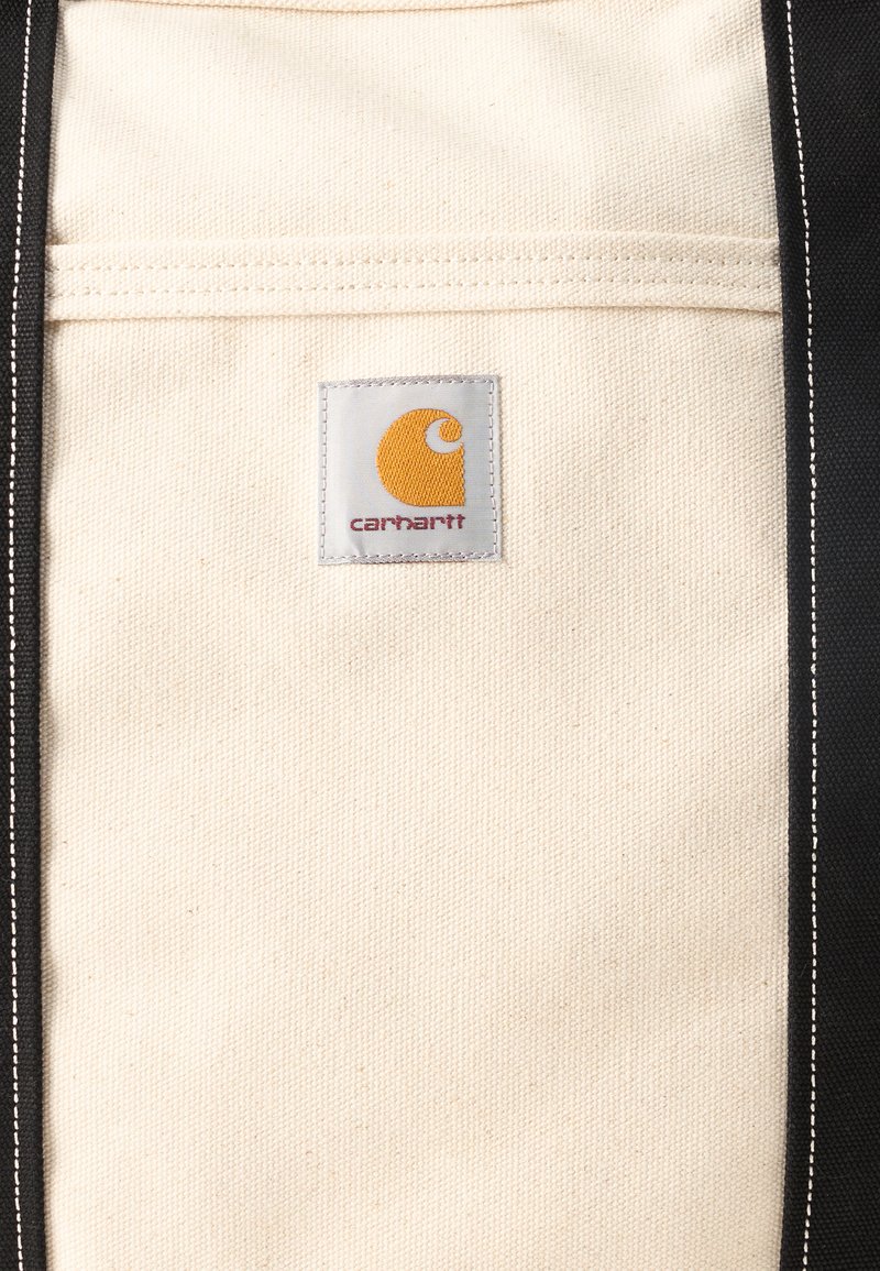 Cream canvas fabric with black edges and a sewn square label featuring an orange Carhartt logo at the center.