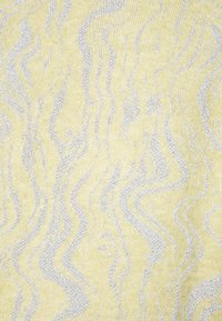 Stickad tyg i ljusgul med vågiga silvermönster. Mjuk textur med en subtil lyster från metalltrådar som är vävda i tyget.