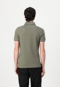 Πράσινη ελαιόλαδου polo μπλούζα από βαμβάκι με κοντούς μανίκους, που διαθέτει αντίθετο τελείωμα γύρω από τον γιακά και τους μανικιών. Απλός σχεδιασμός, χαλαρή εφαρμογή.