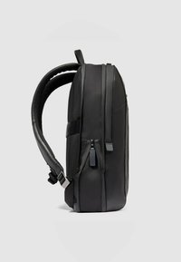 Zwarte rugzak met een strak ontwerp, gemaakt van duurzame materialen. Voorzien van gevoerde banden, zijkanten met ritsen en gestructureerde accenten. Zijaanzicht.