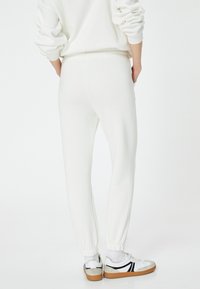 Witte sweats met elastische boorden en tailleband, gemaakt van zachte stof. Draagt zich met witte en zwarte sneakers met een rubberen zool.