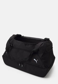 Sac de sport noir en tissu durable, doté de doubles zips, d'un intérieur spacieux, d'une poche en maille sur le côté et du logo Puma à l'avant.