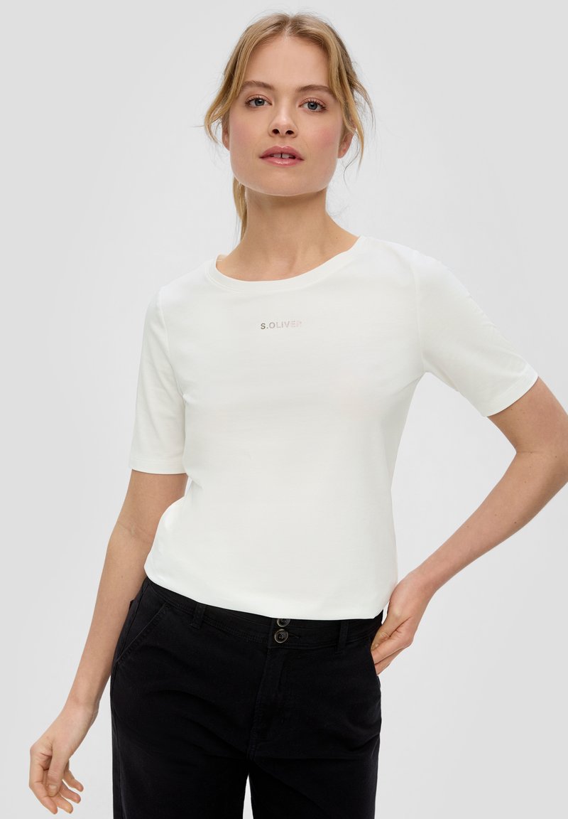 Weißes T-Shirt mit kurzen Ärmeln und rundem Ausschnitt, dezent mit "S. OLIVER"-Branding in metallischer Druck auf der Brust, kombiniert mit schwarzen Hosen.