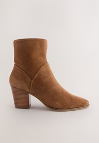 Bruine suède enkellaars met een puntige neus, met een taps toelopend ontwerp en een gestapelde houten hak. Gladde textuur met minimale stiksel details.