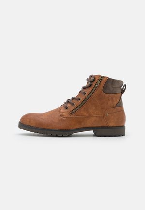 Bottine en cuir marron à lacets avec fermeture éclair latérale et col matelassé marron foncé sur une semelle noire crantée.