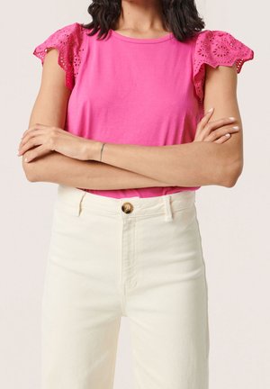 Rosa Baumwoll-T-Shirt mit Spitzenbesatz an den kurzen Ärmeln, kombiniert mit hochgeschnittenen, cremefarbenen Jeans aus Denim mit Knopfverschluss.