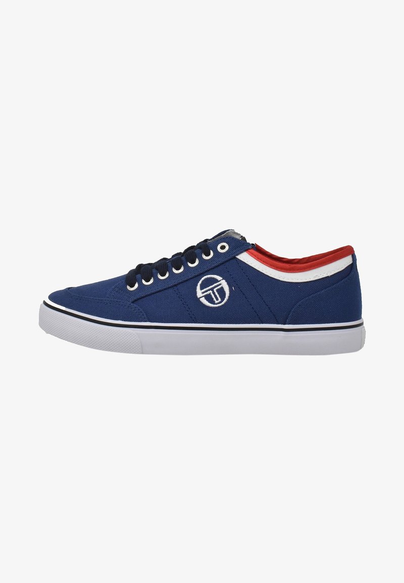 Baskets basses en toile bleue avec lacets noirs, semelle blanche, logo blanc sur le côté, et bordure rouge et blanche autour du col de la cheville.