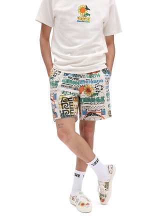 Hvid bomulds-T-shirt med et farverigt solsikketryk. Multifarvede bomuldsshorts med forskellige miljøtema-grafikker. Hvide sneakers og sokker.