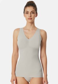 Débardeur gris clair en V, fabriqué en tissu lisse et extensible, avec des bretelles larges, conçu pour une silhouette ajustée, atteignant les hanches.