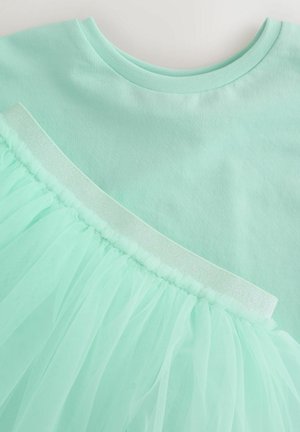 Mintroheline ülemine osa pehme puuvillase materjaliga; allääril tüllist volang, mille äär on kaunistatud läikiva elastse triibuga lisadetailina.