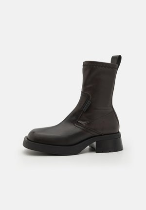 Czarne skórzane botki za kostkę o gładkiej fakturze, okrągłym nosku i stabilnym obcasie w kształcie bloku. Posiadają boczny zamek błyskawiczny oraz pętelkę do łatwego zakładania.