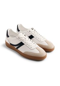 Sneaker bianchi e beige con finitura in pelle e camoscio. Presentano strisce di accento nere, punta rotonda e suola in gomma testurizzata.