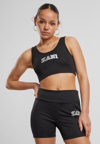 Čierny športový crop top a šortky so záberom "KANI". Hladká tkanina, priliehavý strih, bez vzorov, ktorý zdôrazňuje jednoduchosť a funkčnosť.