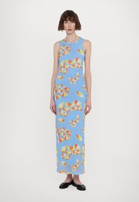 Robe maxi en tissu bleu clair présentant un motif géométrique de formes colorées en rouge, jaune et blanc. Modèle sans manches, longueur aux chevilles.