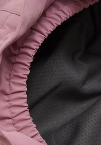Ljusrosa tyg med rynkad elastisk kant som avslöjar en svart strukturerad innerfoder. Slät utsida med subtil lyster och inget synligt mönster.