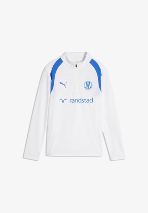 Camiseta deportiva blanca de manga larga con detalles azules en los hombros, logotipo de Puma, escudo del club y patrocinador Randstad en la parte delantera. No hay personas presentes.