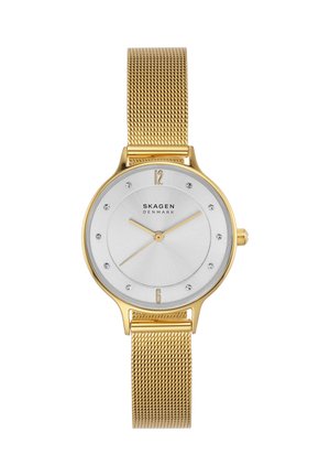 Zegarek z złotą siateczkową bransoletą, białą tarczą, złotymi wskazówkami, kryształowymi indeksami godzin oraz napisem „Skagen Denmark” na środku.