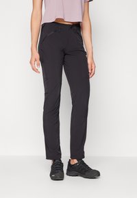 Pantalones exteriores negros con un diseño ajustado, que cuentan con bolsillos con cremallera y una tela ligera y duradera. Acompañados de unas botas de senderismo negras.