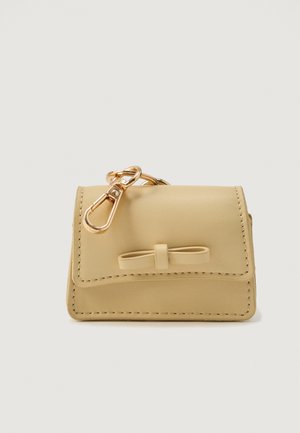 Beige leather key pouch with stitched edges, a small bow detail on front, and a gold-tone metal keyring clasp attached on top.