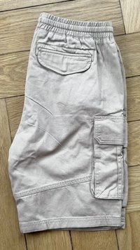 Lichtgrijze cargoshorts met een elastische tailleband, voorzien van zijzakken, een achterzak en een geweven stof. Platte naden zijn zichtbaar.