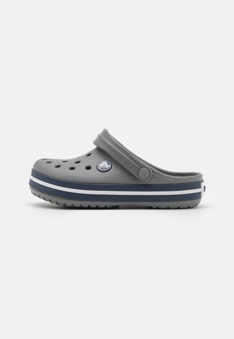 Grijze Crocs klompen met ventilatiegaten, een contrasterende donkerblauwe streep en een circulair logo, gemaakt van lichtgewicht, duurzaam materiaal.
