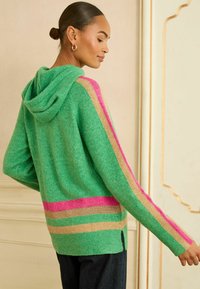 Grüner gestrickter Hoodie mit rosa, goldenen und blauen Streifen, in lockerer Passform und mit seitlichen Schlitzen. Strukturierter Stoff mit weichem Aussehen.